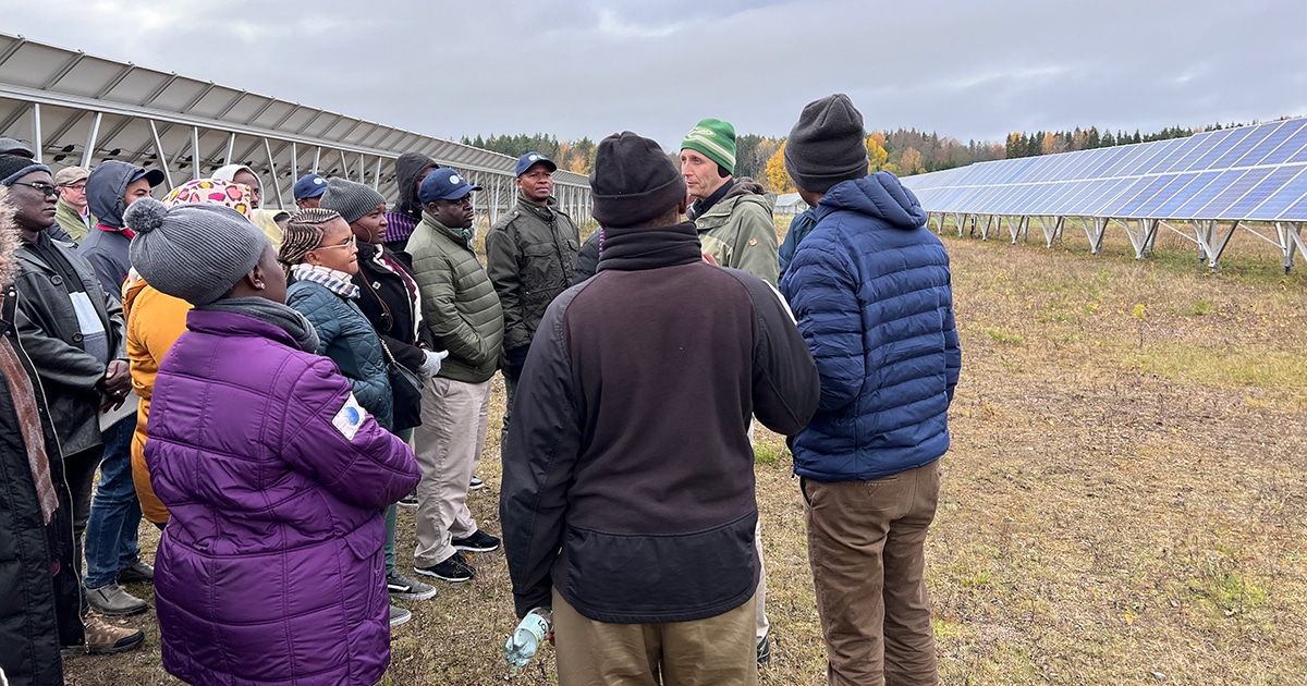 Participants during study visit at Glava Energy Center with solar panels in the background.